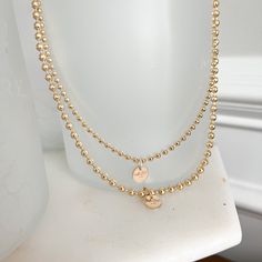 This Logo Ball Chain Gold Necklace brings a modern twist to a timeless classic. Its signature logo charm sits atop a water-resistant gold ball chain, creating a sophisticated and exclusive accessory perfect for making a statement and displaying unique style. Measures 16” Logo charm is 14 karat gold filled. Choose small ball chain or medium ball chain size. Comes boxed. Made in USA. Gold-plated Ball Chain Necklace, Perfect As A Gift, Gold Plated Charm Necklaces With Satellite Chain, Gold-plated Gold Charm Necklace With Satellite Chain, Gold Plated Gold Charm Necklace With Satellite Chain, Gold-tone Gold-plated Satellite Chain Necklace, 14k Gold Filled Ball Chain Necklace, Gold-tone Satellite Chain Necklace, Gold Plated Charm Necklace With Satellite Chain, Gold Charm Necklace With Satellite Chain For Everyday