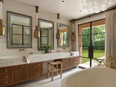 a large bathroom with two sinks, mirrors and a bathtub in the middle of it