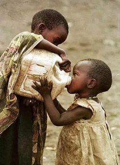 two young children are playing with something in the dirt and mud, while one child is holding on to it's back