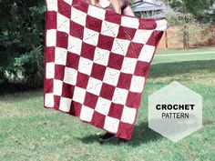 a woman holding up a red and white checkered quilt in front of her face