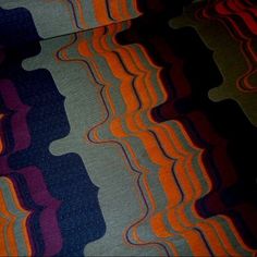 an orange, blue and purple striped fabric with wavy lines on the bottom half of it