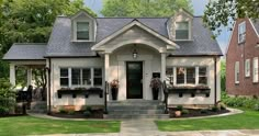 a white house with black shutters on the front door and two windows in it