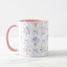 a pink and white floral mug sitting on top of a marble counter next to a wall