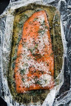 a piece of salmon covered in parmesan cheese and seasoning sitting on top of aluminum foil