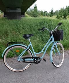 a blue bike parked on the side of a road next to a field and bridge