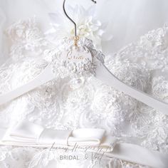 a wedding dress with a white flower on it and a name tag attached to the back