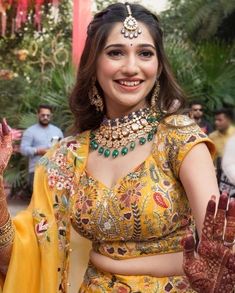 a woman in a yellow outfit with jewelry on her head and hands, smiling at the camera