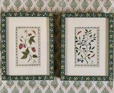 two framed pictures with flowers and leaves in them on a wallpapered pattern background