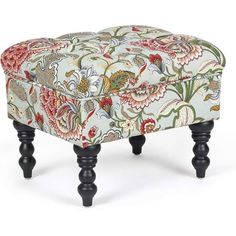 an upholstered foot stool with black legs and floral fabric on the top, in front of a white background