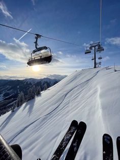 the ski lift is going down the snowy hill with skiers on it's side