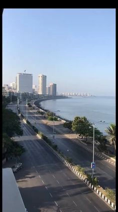 an empty street next to the ocean with tall buildings in the background