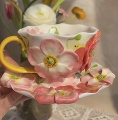 a hand holding a coffee cup with flowers on it