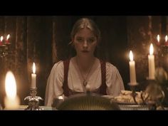 a woman sitting at a table surrounded by candles