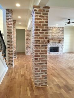 an empty living room with wood floors and brick fireplace