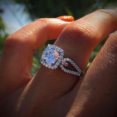 a close up of a person's hand holding an engagement ring