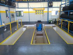 the inside of a car repair shop with yellow and white lines on the floor, two rows of tires