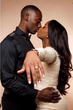 a man and woman kissing each other with their hands on the forehead, in front of a brown background