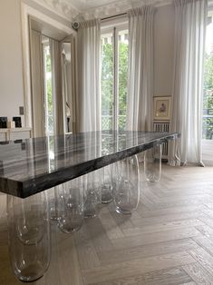 a long table with clear glass vases on it in front of a large window