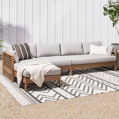 a couch sitting on top of a rug next to a potted plant and wooden table