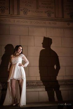 a woman standing in front of a wall with her shadow on the wall behind her