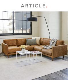 a living room with brown leather couches and a white coffee table in front of a large window