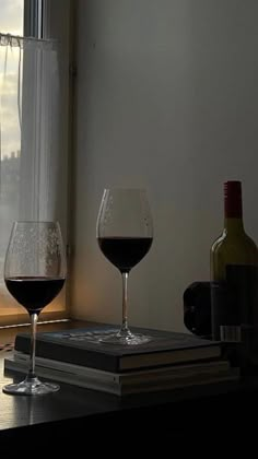 two wine glasses sitting on top of a table next to a window