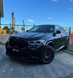 a black bmw x4 parked in front of a building on the side of a road