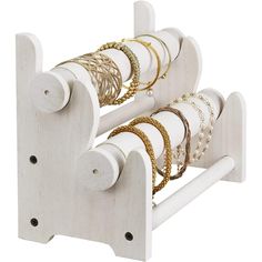 a white wooden rack with bracelets and rings hanging from it's sides, on a white background