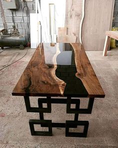 a table made out of wood and metal with a glass top on the bottom, sitting in a room