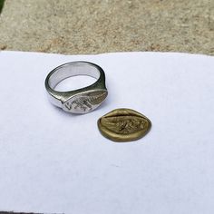 a ring sitting on top of a piece of paper next to a small gold coin