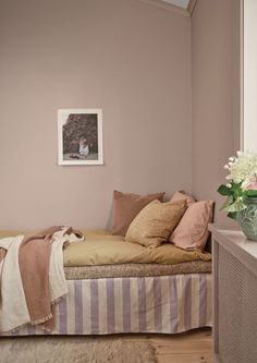 a bed with pillows and blankets on top of it in a bedroom next to a window