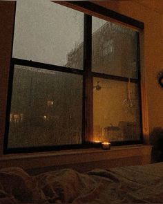 a bedroom with a window that has candles lit up in the windowsill and on the bed