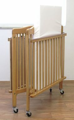 a baby crib with a pillow on top of it and wheels to the side