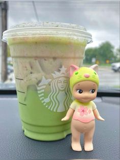 a toy cat next to a starbucks cup on a car dashboard with the lid up