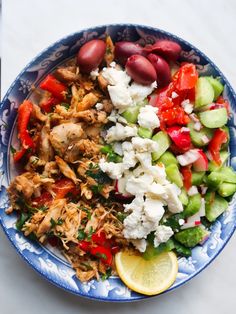 a blue and white bowl filled with lots of different types of food on top of a table