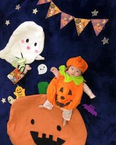 a baby in a pumpkin costume on a blue background with halloween decorations and bunting