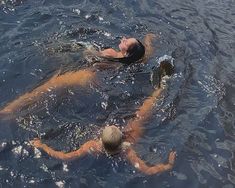 two people are swimming in the water with one person wearing a life jacket and hat