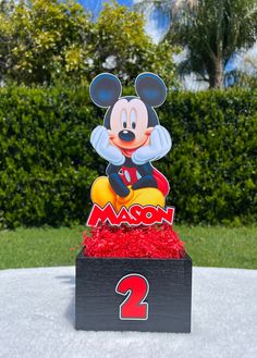 a mickey mouse centerpiece sitting on top of a wooden box filled with red flowers