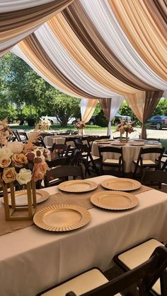 a table set up for an event with plates and napkins on it, along with flowers