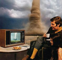 a man and woman sitting in front of a television with a tornado coming out of the background