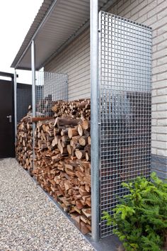 a pile of wood sitting in front of a building next to a metal fence and bushes