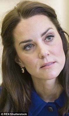 a close up of a person wearing a blue shirt and earrings, looking at the camera