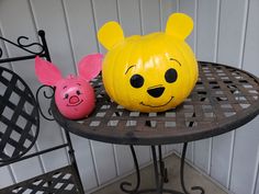 two pumpkins with faces painted on them sitting on a table next to each other