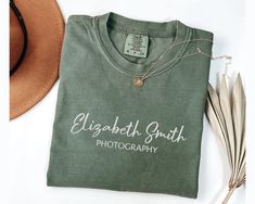 a t - shirt that says elizabeth smith photography next to some feathers and a hat