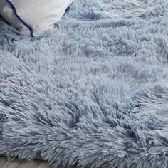 a blue shaggy rug with white pillows on top of it and a pillow in the middle