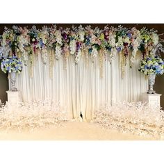 an image of a wedding stage setting with flowers on the wall and white drapes