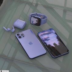 three iphones and earphones sitting on top of a glass table next to each other