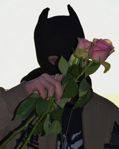 a person wearing a batman mask holding roses