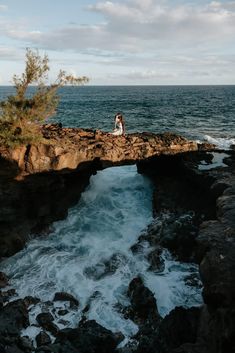 a person sitting on top of a rock near the ocean