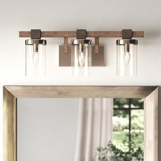 a bathroom mirror with three lights above it and a table in front of the mirror